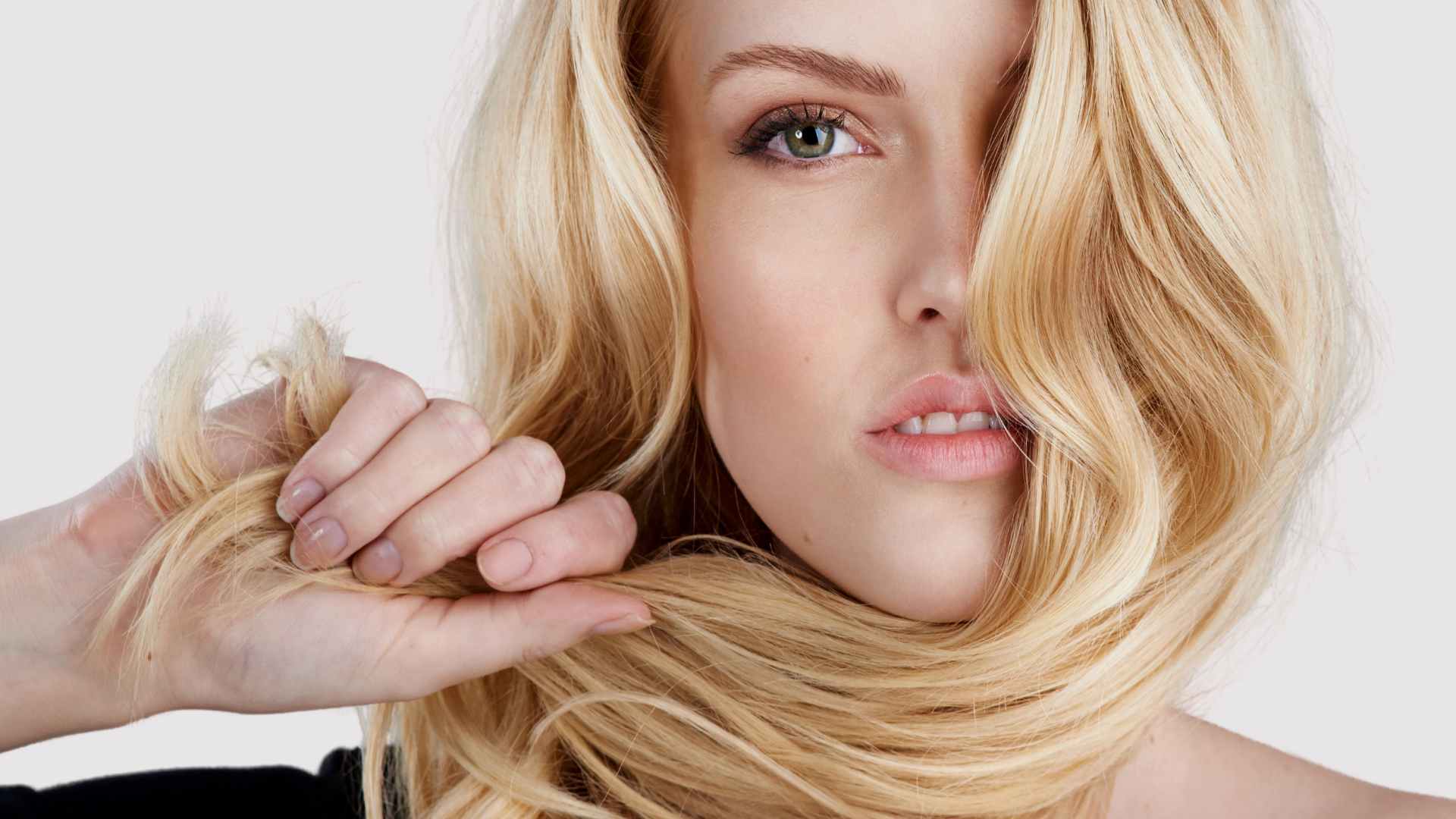 blonde female looking directly at camera holding hair