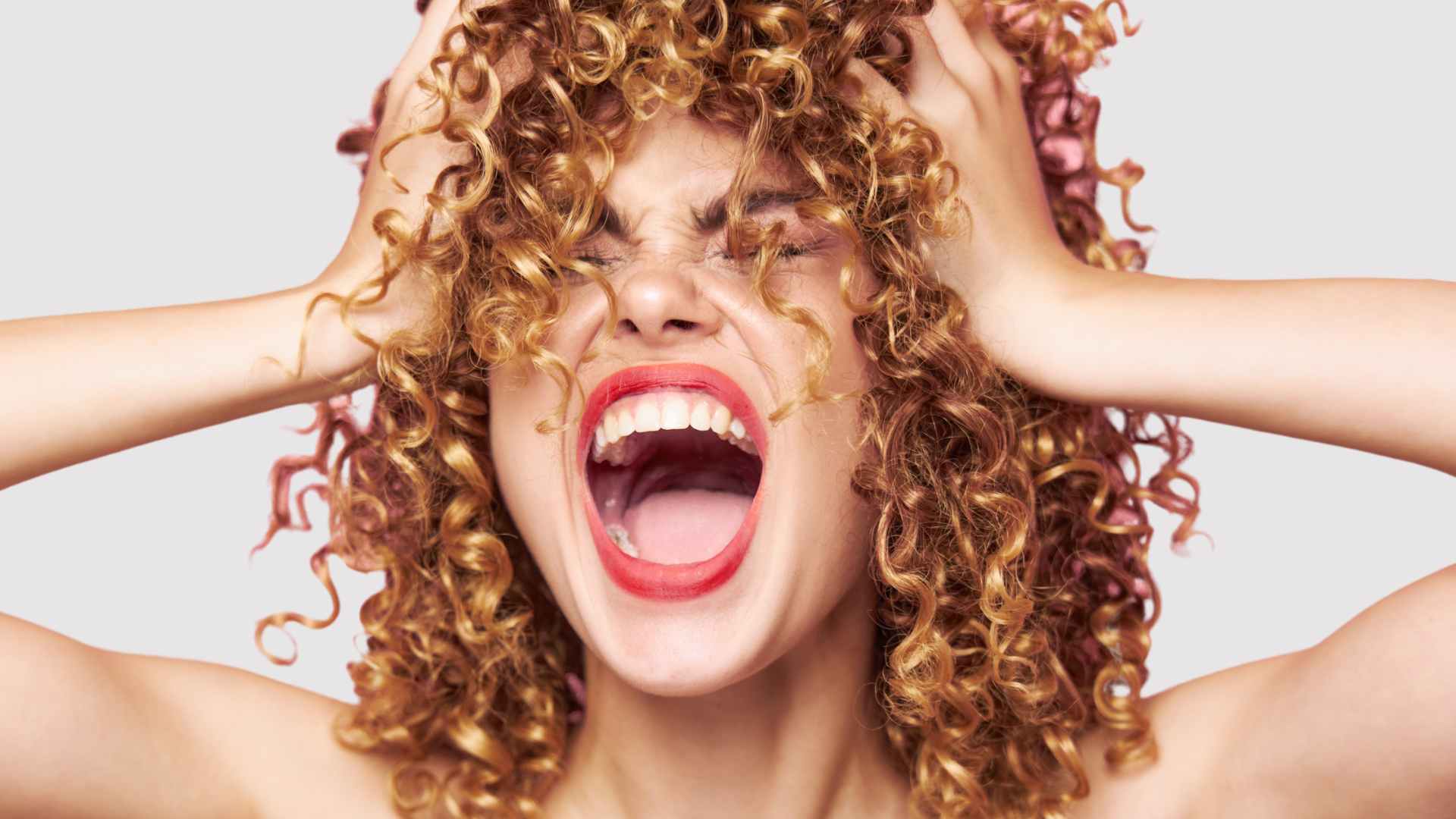 Damaged hair: Female with curly frizz free hair screaming with red lipstick