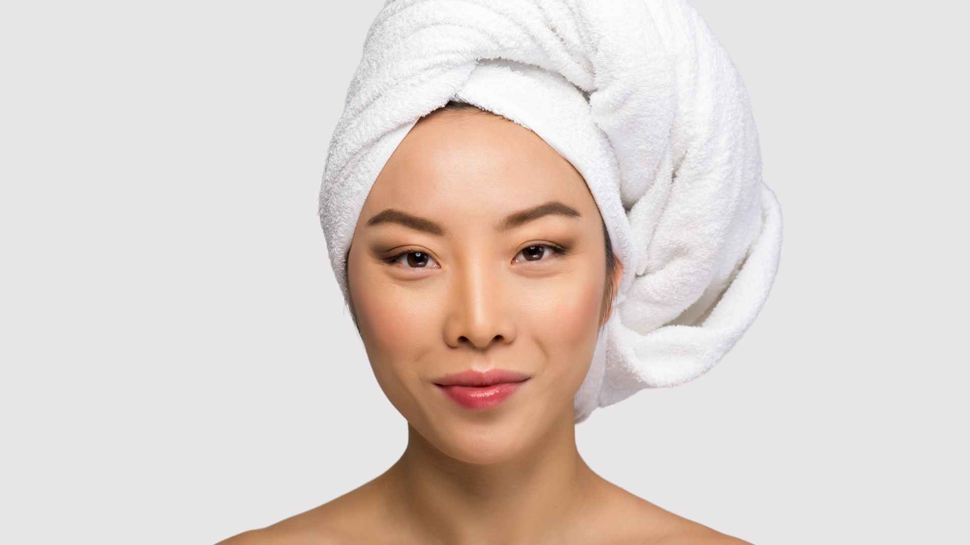 Smiling woman with towel on her head in preparation for a bouncy blow dry