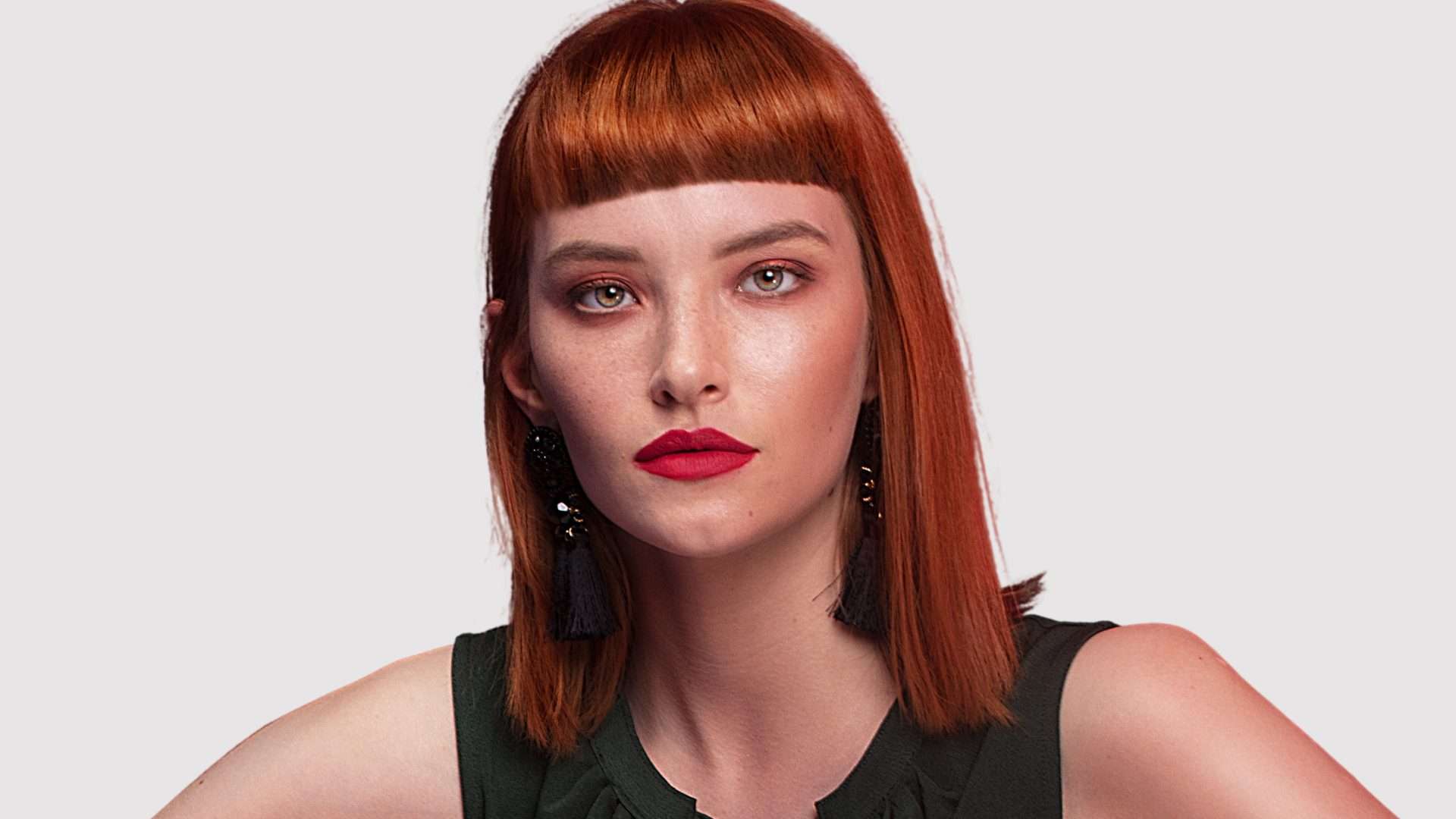 Red haired female model with a full fringe to demonstrate volume in the fringe 