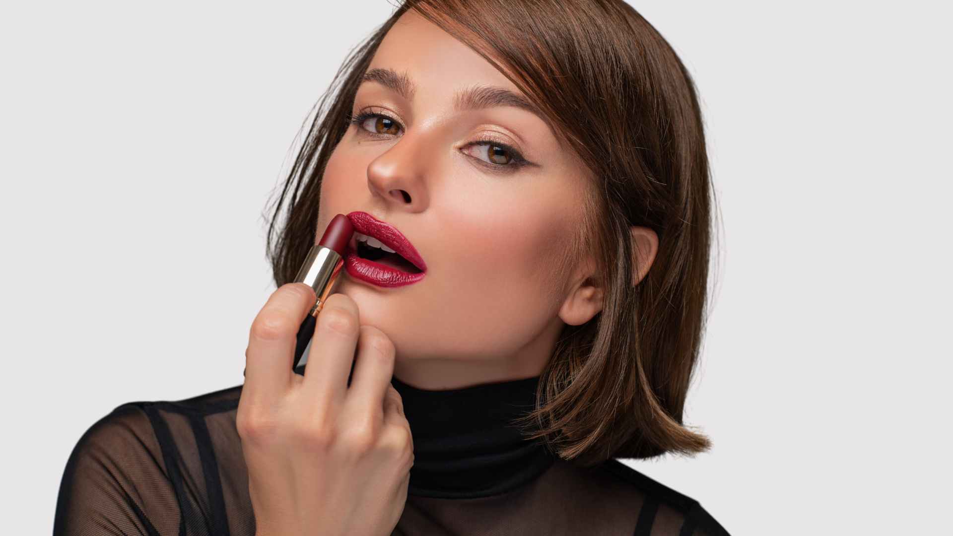 Female with sleek short bob haircut applying lipstick
