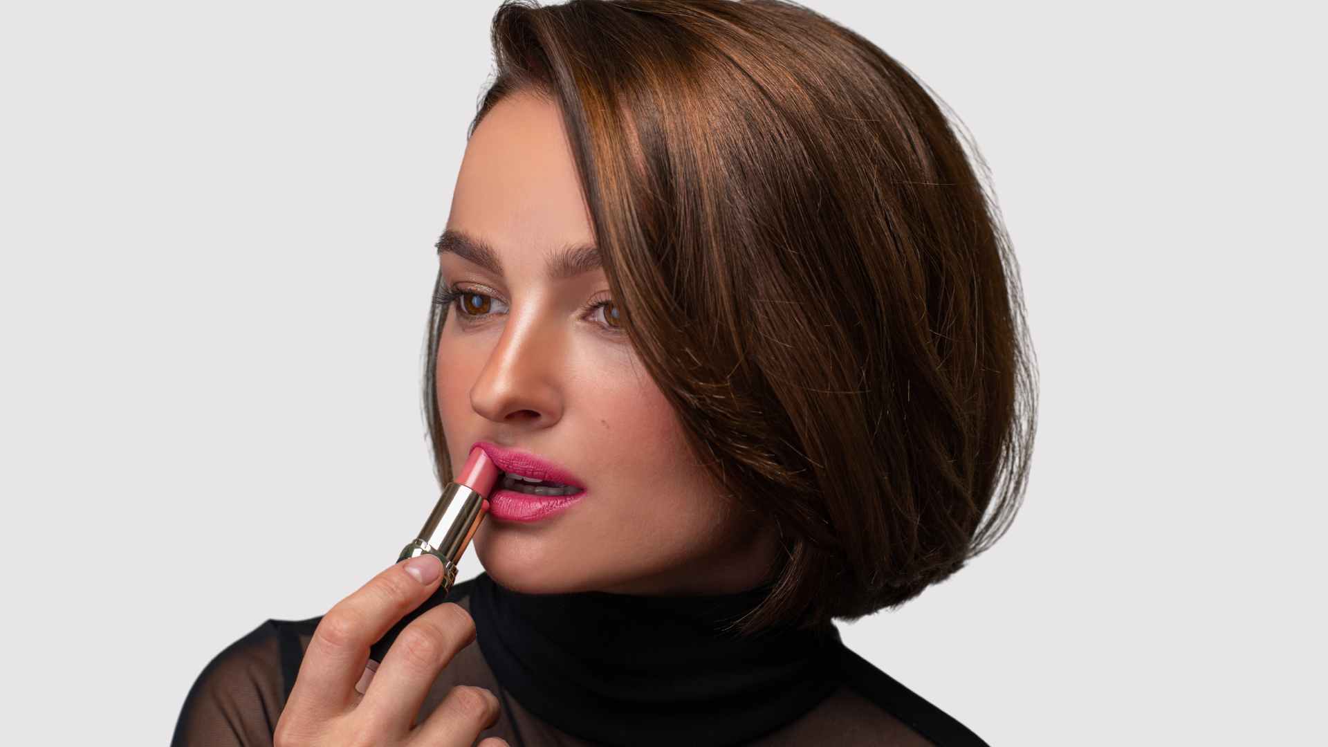 Female applying lipstick with sleek bob hairstyle 