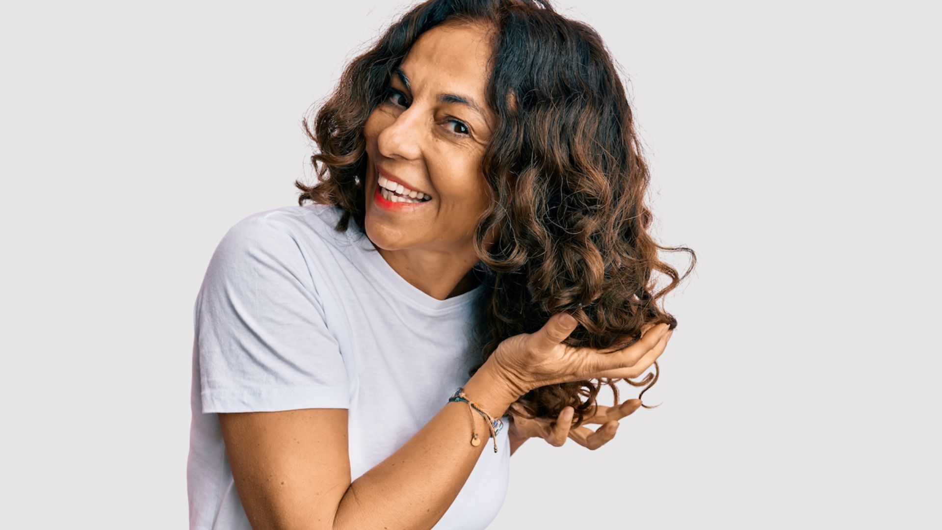smiling female wit mid-length curly hair, holding hair ready for deep hair conditioner
