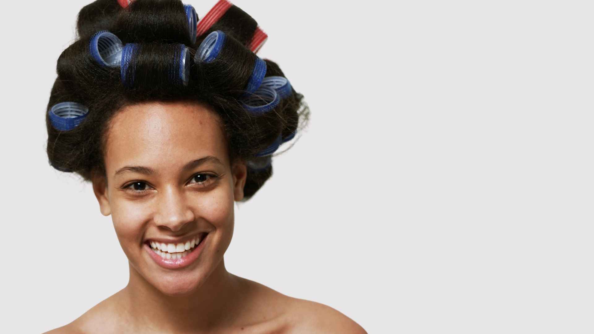 Smiling young woman with velcro rollers in her hair