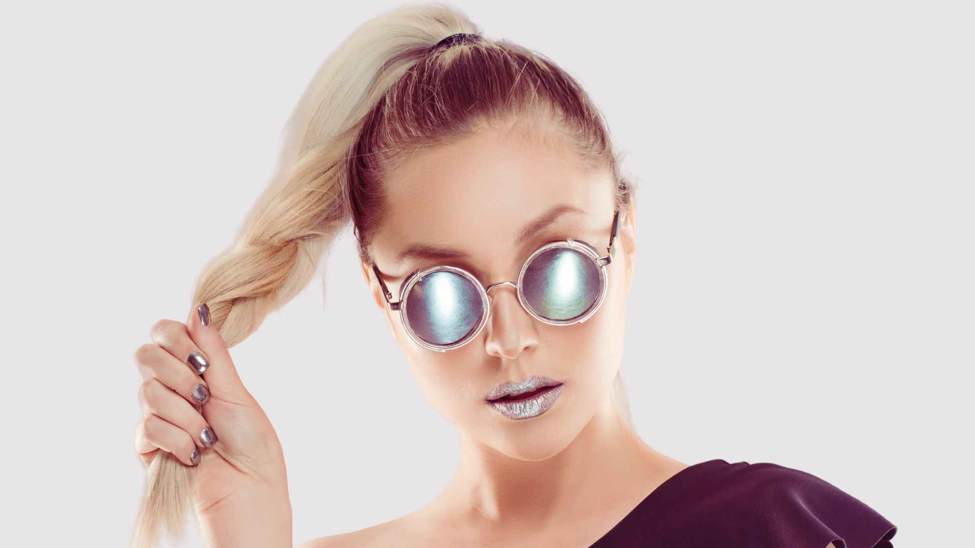 Female model wearing sunglasses holding hair in a twisted ponytail