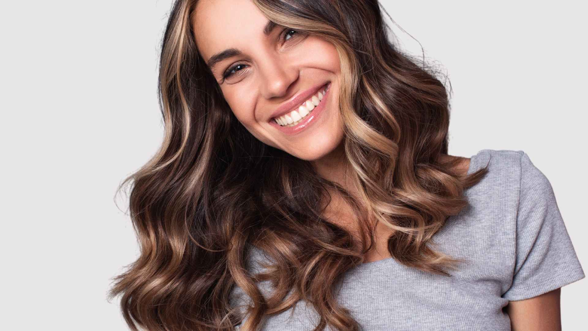 smiling female model, long brown healthy dyed hair with highlights