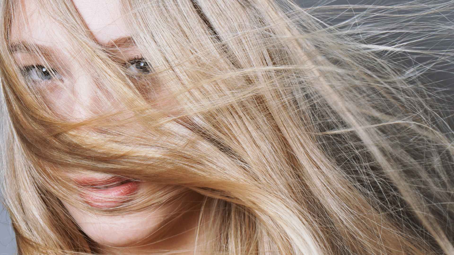 female with long blonde hair and split ends. Hair over her face.