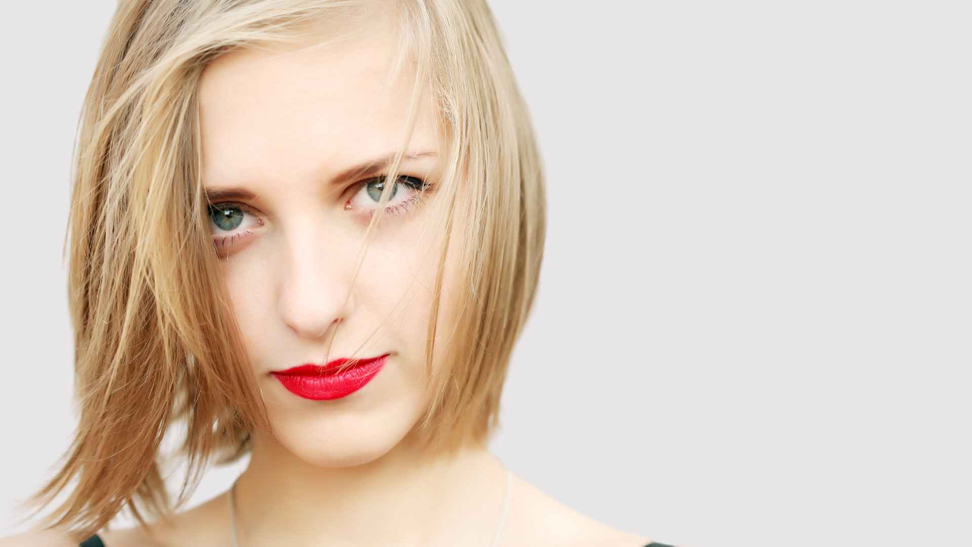 blonde female with fine hair, wearing red lipstick looking directly at the camera