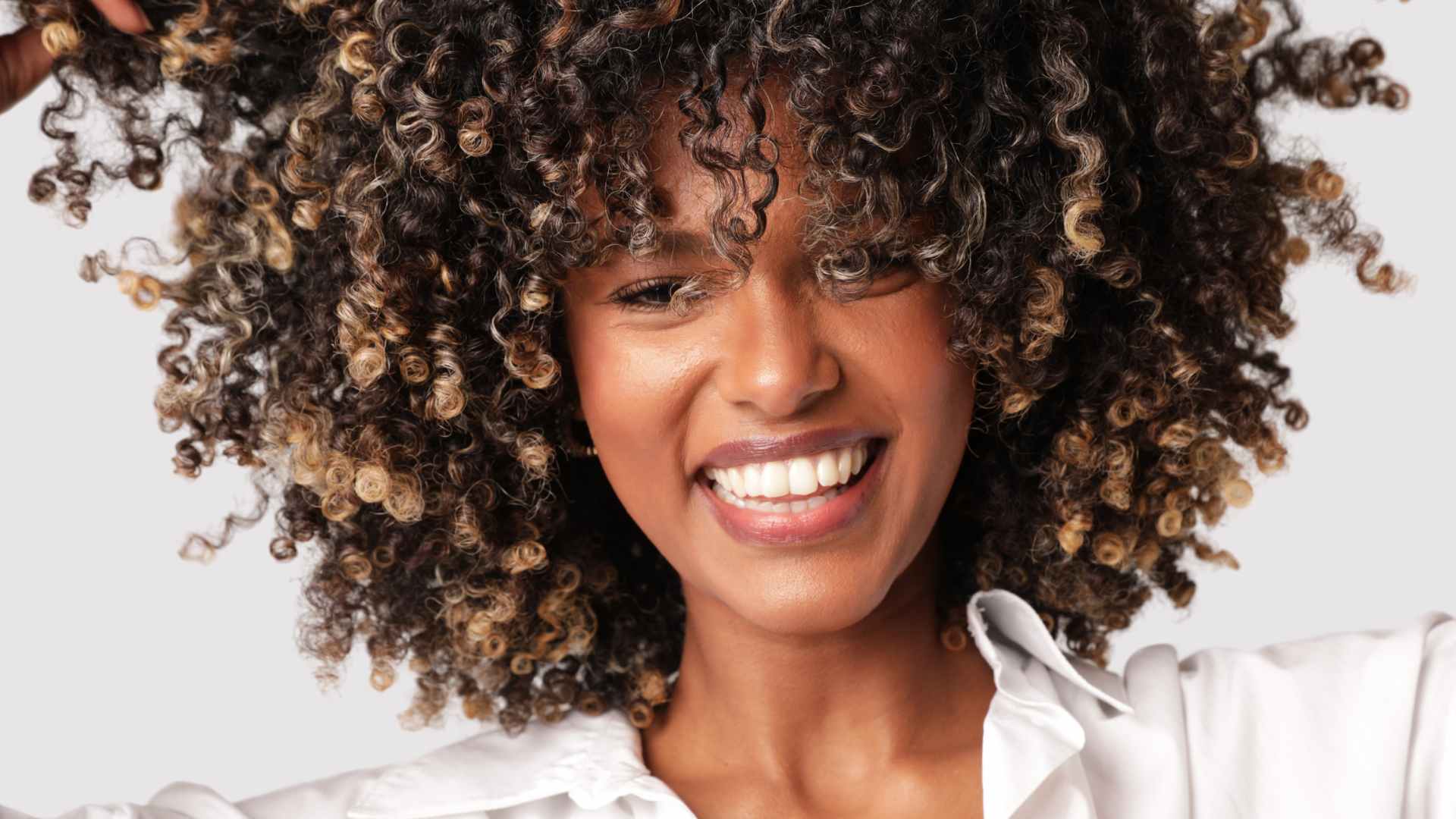 Portrait of joyful woman with afro hair smiling over white background. Isolated. High quality photo.